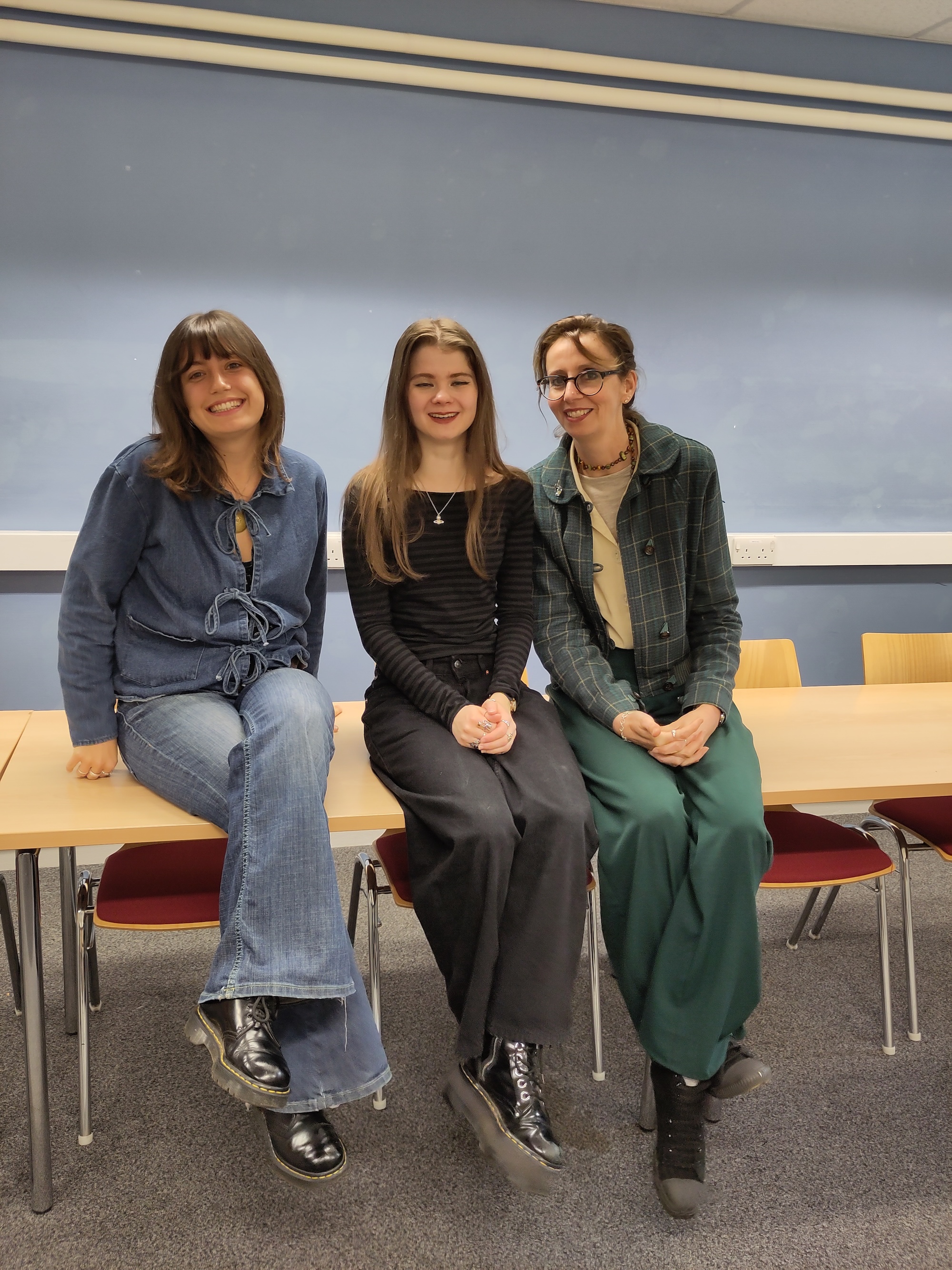 Two students and an academic sitting on a table
